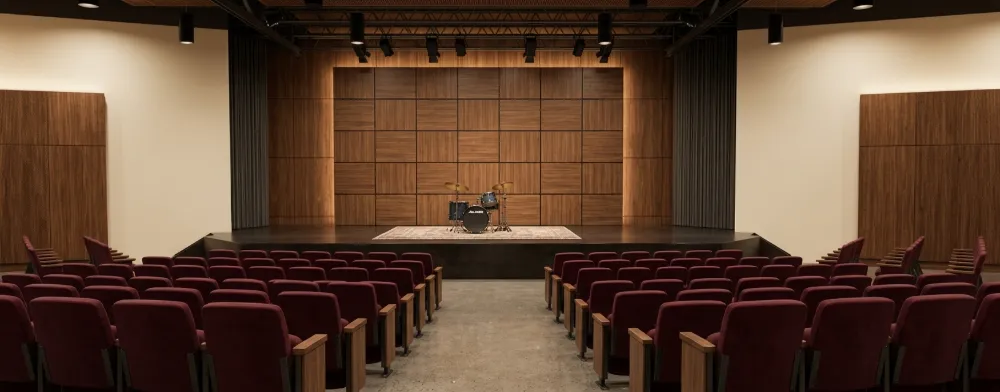 Render of an auditorium with a wood-paneled stage and red upholstered seating